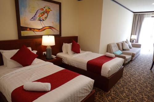 une chambre d'hôtel avec deux lits et un canapé dans l'établissement MM Heritage Hotel, à Malacca