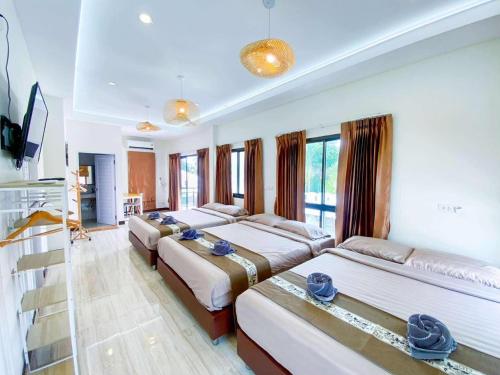 ein Hotelzimmer mit drei Betten und einem Fernseher in der Unterkunft Fhamai Pool Villa Pattaya (บ้านฟ้าใหม่ พูลวิลล่า) in Ban Huai Yai