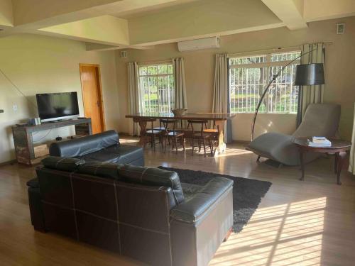 a living room with a leather couch and a table at Casa aconchegante ao lado do Parque de Exposições in São Borja