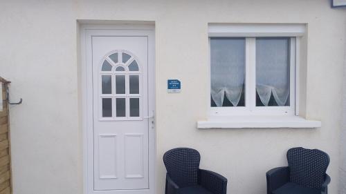 a door and two chairs in front of a house at gite repos et tranquillité M in Cayeux-sur-Mer
