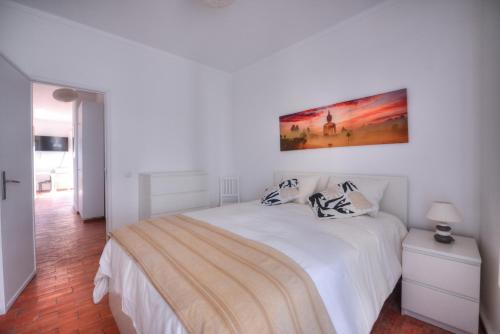 a white bedroom with a bed and a painting on the wall at Margarida Seaview Terrace Apartment in Luz