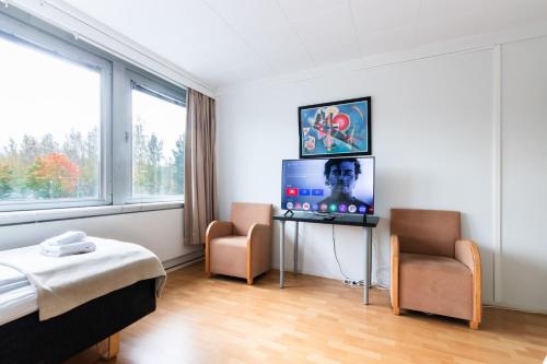 a bedroom with a bed and a tv and two chairs at Functional and cozy 3 bedroom apartment for 6 in Myyrmäki