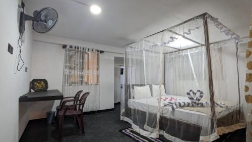 a bedroom with a canopy bed with a desk and chair at Parei Beach Inn in Tangalle