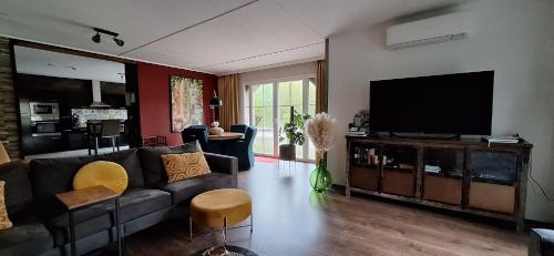 a living room with a couch and a flat screen tv at Vakantiehuisje Meerland43 in Meerland