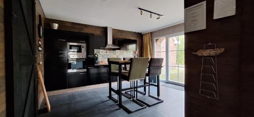 a kitchen with black cabinets and a table and chairs at Vakantiehuisje Meerland43 in Meerland