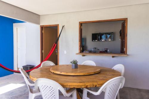 a dining room with a wooden table and white chairs at Chalé 3 Reis Bg in Barra Grande