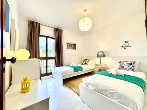 ヴィラモウラにあるVilmaoura Brightness Apartment 1 with Pool by Homingのベッド2台と窓のある寝室