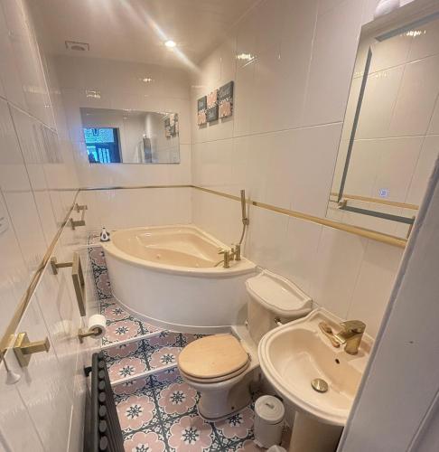 a bathroom with a tub and a toilet and a sink at Bayside - Breathtaking views of the Clyde in Rothesay