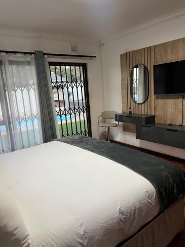 a bedroom with a large white bed and a mirror at 8 on Lorenzo in Amanzimtoti