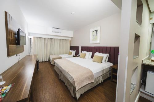 a hotel room with two beds and a television at Hotel Victoria Villa Curitiba by Nacional Inn in Curitiba