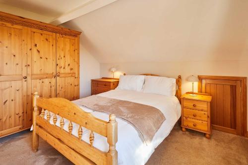 a bedroom with a large bed and wooden cabinets at Host & Stay - Cherry Willows in Stainsacre
