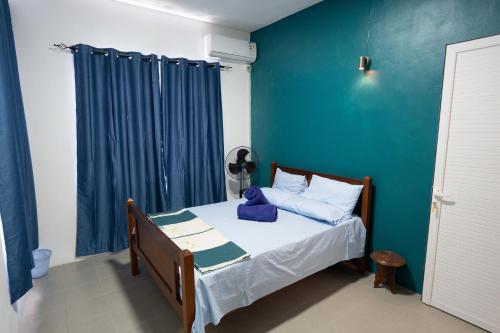 a bedroom with a bed with a blue wall at Spacious Coastal Home Steps from the Beach in Flic-en-Flac