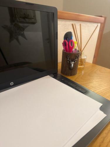 a laptop computer sitting on a desk with a cup of scissors at Appartamento vacanze Piazza in Fondo