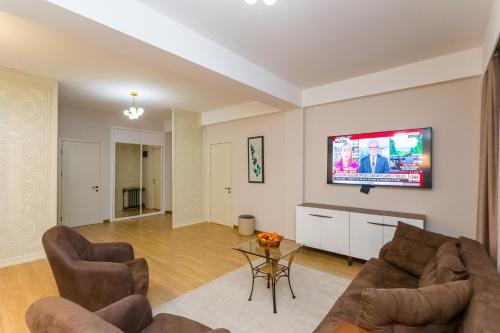 a living room with a couch and a tv on a wall at Central Elegant Apartment in Tbilisi City