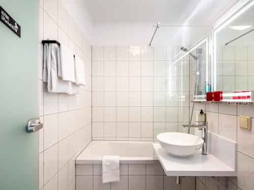 a white bathroom with a tub and a sink at DORMERO Hotel Weimar in Weimar