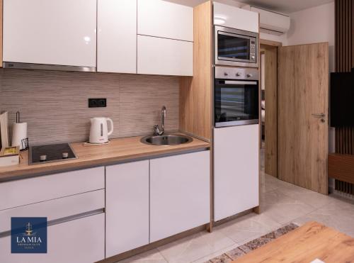 een keuken met witte kasten en een spoelbak bij La Mia Premium Suite in Tuzla