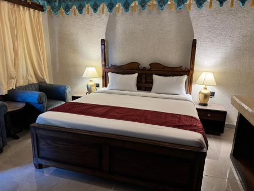 a bedroom with a bed and a chair and lamps at Estherea Bagh Ranthambhore Tiger Territory in Sawāi Mādhopur