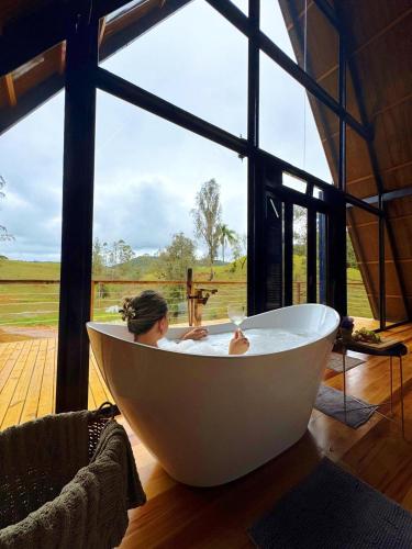 ItaquáにあるChalé de alto padrão Nereuの窓のある部屋のバスタブに座った女性