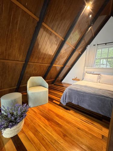 ItaquáにあるChalé de alto padrão Nereuの屋根裏のベッドルーム(ベッド1台、椅子付)