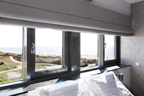 ein Schlafzimmer mit einem Bett mit Blick auf das Meer in der Unterkunft Droomsuites Egmond aan Zee 8 personen by Droomvilla in Egmond aan Zee