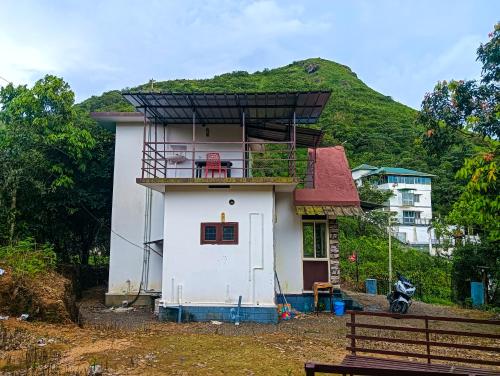 una pequeña casa con balcón en la parte superior en Breezeblow, en Vagamon