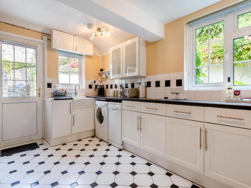 a kitchen with white cabinets and a checkered floor at The Retreat Lulworth in West Lulworth