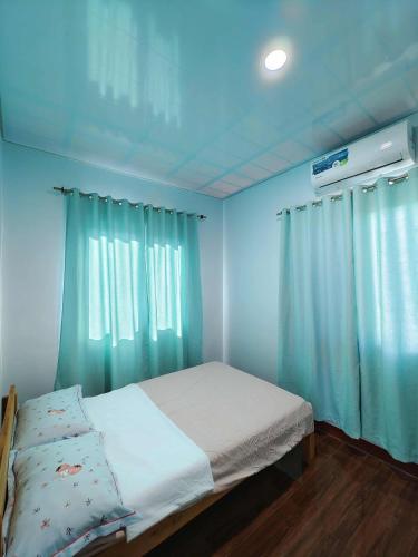 a bedroom with a bed with blue walls and curtains at PA L Residence in Euscara