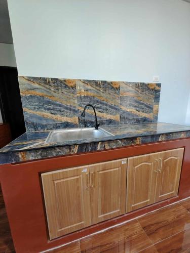 a kitchen counter with a sink and wooden cabinets at PA L Residence in Euscara