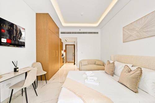 1 dormitorio con 1 cama blanca, escritorio y sillas en Riviera Azure Gateway Superior- 10min to Burj Khalifa, Dubai Mall and Airport and 20min to Marina, en Dubái