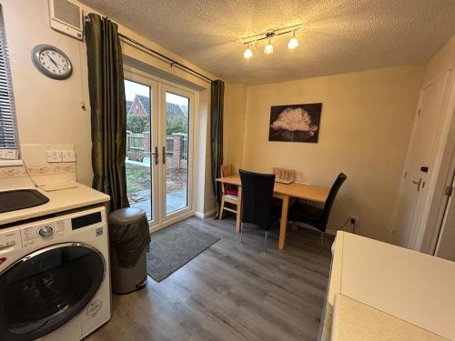 a kitchen and dining room with a table and a clock at 3 Bedroom, Parking, 2 Toilets, Wi-Fi, Modern in Crewe