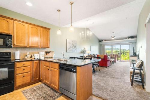 a kitchen with wooden cabinets and a living room at Sunset Daydream - Elegant Condo on Table Rock in Branson