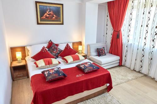 Un dormitorio con una cama con una manta roja y una silla. en Apartament B B Boutik C, en Eforie Sud