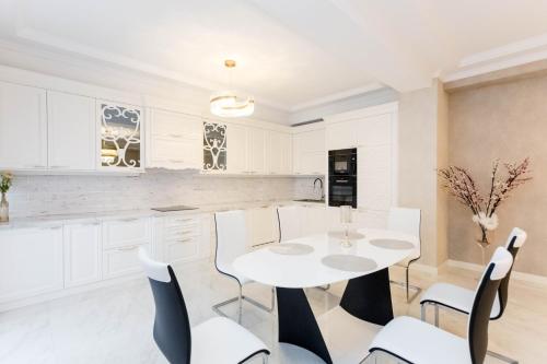 a white kitchen with a white table and chairs at Central Elegant Apartment in Tbilisi City