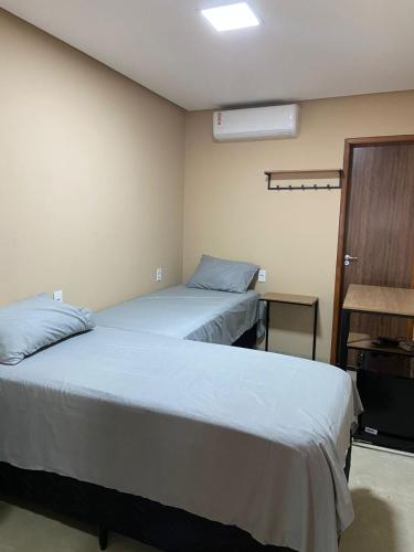 a room with two beds and a window and a door at Hotel Lorenna in Santa Inês