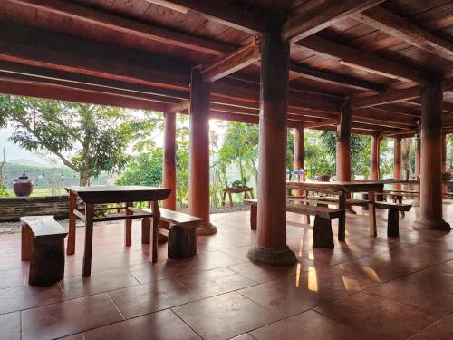 einen Pavillon mit Holztischen und Bänken auf einer Terrasse in der Unterkunft Ruộng Cafe & Homestay in Cao Phong