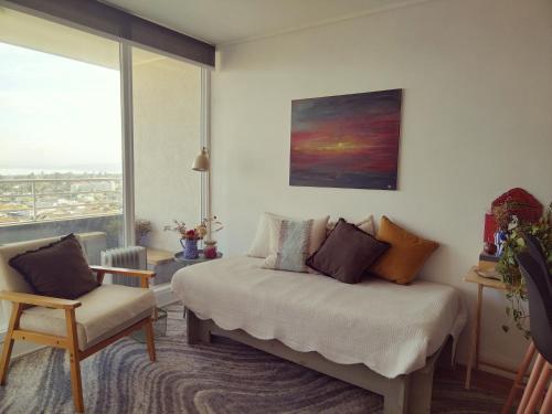a bedroom with a bed and a chair and a window at Despierta con vista al mar en un hogar tranquilo y luminoso in Concón