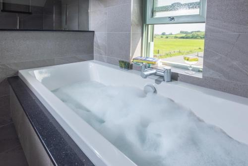 d'une baignoire blanche avec lavabo et d'une fenêtre. dans l'établissement Ellenboro House, Cosy Sleeps 2, Near Cartmel, à Grange-over-Sands