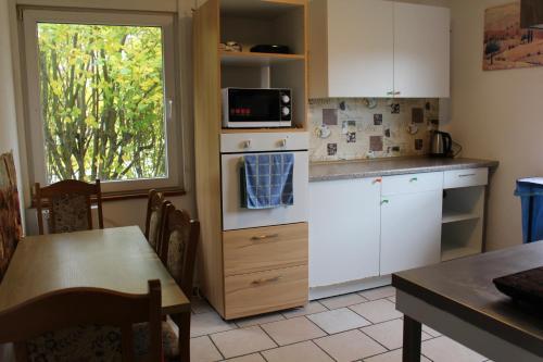 a kitchen with white cabinets and a microwave and a table at Bungalow 1 - 4-Raum-Wohnung mit Küche und 2 WC Duschen in Ohrdruf-Crawinkel in Ohrdruf