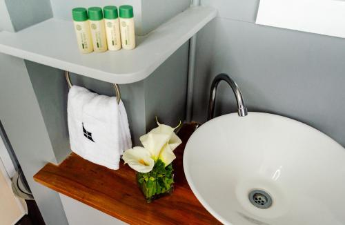 a bathroom with a white sink and a white flower on a shelf at Hotel Bijoux in Plaridel