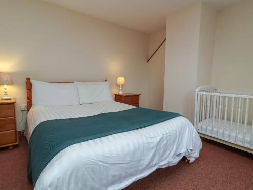 a bedroom with a large bed and a crib at Denhill Cottage in Taunton