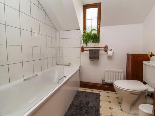 a white bathroom with a tub and a toilet at Denhill Cottage in Taunton