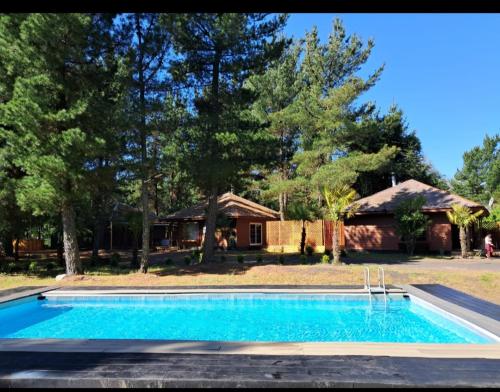 a swimming pool in front of a house at Cabañas Torres Del Bosque in Pucón