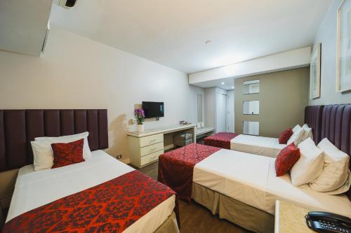 a hotel room with two beds and a desk at Hotel Victoria Villa Curitiba by Nacional Inn in Curitiba
