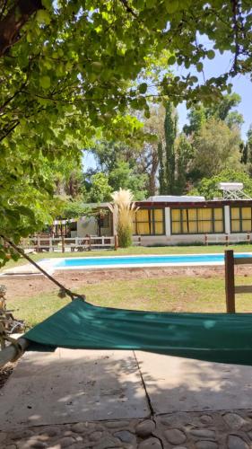 a green hammock in a park with a pool at Hostel Barreal in Barreal