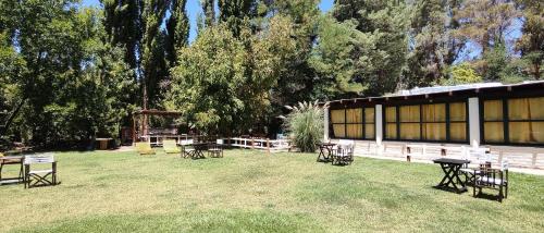 a group of tables and chairs in the grass next to a building at Hostel Barreal in Barreal