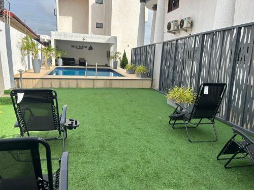 a patio with lawn chairs and a swimming pool at Jessica's Villa in Accra