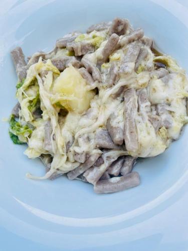 a white plate of food with noodles and broccoli at Hotel Posta in Aprica