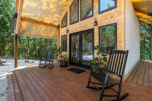 a house with two chairs on a wooden deck at Cedar Creek - Glamping in the Ozarks in Walnut Shade
