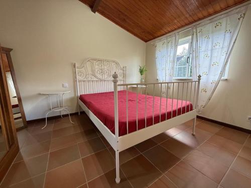 een slaapkamer met een bed met een rode sprei en een raam bij Sobreiros' Studio - Gerês in Terras de Bouro
