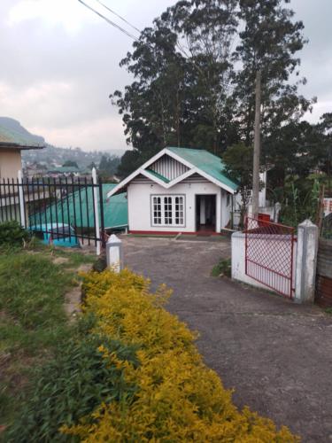 una piccola casa bianca con tetto verde di Nehara Inn a Nuwara Eliya